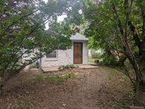 Charming cottage-style home with a textured exterior, classic wood door, and a surrounding of lush greenery at 4209 Perry St, Denver, CO 80212