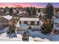 Charming two-story home featuring a well-maintained yard with mature trees and a driveway, all covered in a blanket of snow at 6330 E Irwin Pl, Centennial, CO 80112