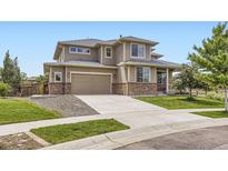 Two story home with a two car garage, brick accents, and mature landscaping at 785 Iris St, Brighton, CO 80601