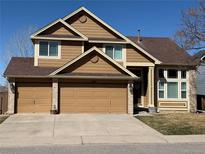 Attractive two-story home featuring a three car garage, large windows, and manicured lawn at 1045 English Sparrow Trl, Highlands Ranch, CO 80129