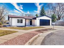 Charming single-story home features stucco and stone accents, a well-manicured lawn, and a spacious two-car garage at 6882 Quail St, Arvada, CO 80004