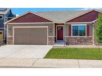 Charming single-Gathering home featuring a well-manicured lawn, attached garage, and tasteful stone accents at 11129 Paradise Ln, Firestone, CO 80504