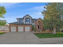 Inviting brick home boasts a three-car garage and beautifully landscaped front yard at 10125 Quarry Hill Pl, Parker, CO 80134