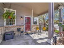 Charming front porch with seating area, potted plants, and a welcoming red door at 19447 E Bellisario Creek Dr, Parker, CO 80134