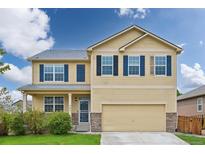 Charming two-story home featuring a 2-car garage, covered porch, and manicured lawn at 443 Hermosa St, Brighton, CO 80603