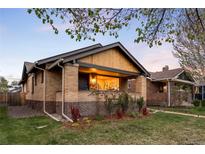 Charming brick home with a well-manicured lawn and inviting front porch with mature trees overhead at 1918 S Lincoln St, Denver, CO 80210