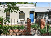 Charming home exterior featuring a blue front door, brick fence, and well-maintained landscaping at 361 Elati St, Denver, CO 80223