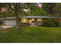 Charming single Gathering home featuring a brick exterior, attached garage and landscaped yard at dusk at 8269 Zephyr St, Arvada, CO 80005