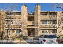 Multi-level condo building featuring stone accents, balconies, and parking area on a sunny day at 1074 S Dearborn St # 107, Aurora, CO 80012