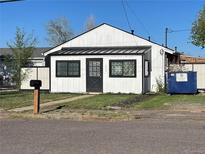 Charming white home with a black door and decorative windows, complemented by a well-maintained green lawn at 1910 Altura Blvd, Aurora, CO 80011
