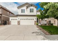 Charming two-story home with a three-car garage, stone accents, and manicured lawn at 11725 Helena St, Commerce City, CO 80022