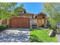 Charming home featuring a stone facade, wood garage door, and inviting front porch at 1007 Nob Hill Rd, Evergreen, CO 80439
