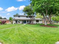 Expansive front yard showcasing lush lawn and mature trees, framing the charming two-story home at 6111 W Fremont Dr, Littleton, CO 80128