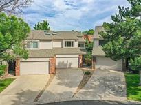 Townhome exterior featuring a two-car garage, brick accents, and mature trees at 12658 W 1St Pl # 78, Denver, CO 80228