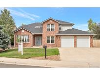 Inviting two-story brick home featuring an attached two-car garage and lush green lawn at 801 S 15Th Ave, Brighton, CO 80601
