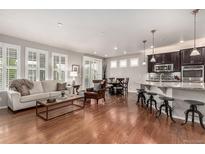 Bright, open-concept living area flows into kitchen and dining, with hardwood floors and plantation shutters at 7991 Heritage Dr, Thornton, CO 80602