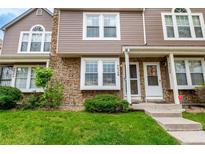 A townhome featuring a stone and vinyl exterior, a well-manicured lawn, and a cozy front porch at 4636 S Dillon Ct # B, Aurora, CO 80015