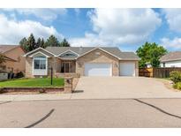 Charming brick home featuring a three-car garage and beautifully manicured front lawn at 1809 Little Bear Ct, Longmont, CO 80504