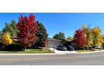 A beautiful single-story home with a lawn, fall foliage, an attached garage, and a concrete driveway at 5030 Titan Ct, Denver, CO 80239