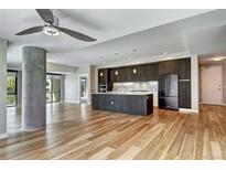 Bright living room featuring wood floors, a concrete pillar, and an open layout to a modern kitchen at 4200 W 17Th Ave # 235, Denver, CO 80204