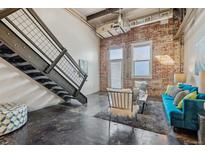 Bright living room featuring exposed brick, staircase, concrete floors, and a modern sofa at 1111 Osage St # 29, Denver, CO 80204