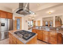 An open kitchen featuring stainless steel appliances and a central island with a gas cooktop and a modern range hood at 2673 S Cook St, Denver, CO 80210