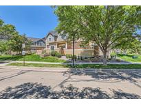 Inviting street view of townhomes featuring stone accents, manicured lawns, and mature trees at 12856 Jasmine St # E, Thornton, CO 80602