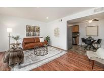 Cozy living room with a brown leather sofa, area rug, and access to the kitchen and dining area at 5300 E Cherry Creek South Dr # 1327, Denver, CO 80246