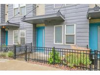 Charming townhome with blue door, gray siding, and landscaped front yard with black metal fencing at 1285 W 9Th Ave, Denver, CO 80204