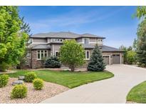 Elegant two-story home boasts a three-car garage, manicured lawn, and a charming stone and siding facade at 5334 Sedona Dr, Parker, CO 80134