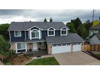 Charming two-story home featuring a three-car garage, blue siding, and brick accents, situated on a well-manicured lawn at 7404 La Quinta Ln, Lone Tree, CO 80124