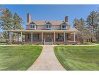 Charming brick home featuring a welcoming front porch, well-manicured lawn, and classic architectural details at 38666 County Road 21, Elizabeth, CO 80107
