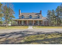 Charming two-story home featuring a brick facade, covered front porch, and manicured lawn at 38666 County Road 21, Elizabeth, CO 80107