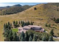 Luxury home with a terracotta tile roof surrounded by evergreen trees and grassy hillsides at 6634 Window Rock Ln, Morrison, CO 80465