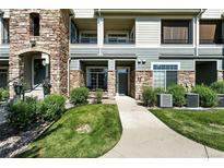 Charming condo features a stone facade, manicured lawn, and inviting walkway leading to a private entrance at 474 Black Feather Loop # 406, Castle Rock, CO 80104