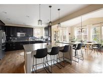 Stylish kitchen with black cabinets, granite countertops, stainless steel appliances and a seamless transition to the dining area at 3472 Harvard Pl, Broomfield, CO 80023