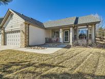 Charming home with a two-car garage, stone accents, manicured lawn and welcoming front porch under a clear blue sky at 2227 Chestnut Cir, Erie, CO 80516