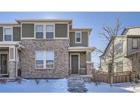 Two-story brick home with gray accents, snowy front yard, and a walkway leading to the front door at 16630 E Virginia Ave, Aurora, CO 80017