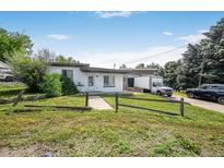Charming single-story home featuring a well-maintained lawn, rustic fence, and a bright white exterior paint at 1020 Kipling St, Lakewood, CO 80215