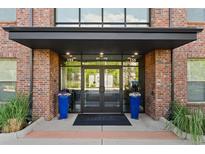 Modern building entrance with brick exterior, double doors, and attractive landscaping at 155 S Monaco Pkwy # 114, Denver, CO 80224