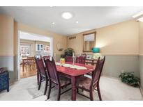 Traditional dining room with cherry wood table and chairs, and views into kitchen at 4621 S Perry Way, Denver, CO 80236