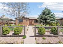 Charming brick home featuring a fenced yard with lush greenery, mature trees, and inviting pathway at 3580 Locust St, Denver, CO 80207