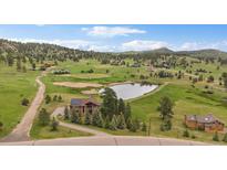 Stunning aerial view of home on acreage with pond, trees and mountain views at 7082 Silverhorn Dr, Evergreen, CO 80439