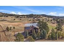 Secluded mountain home features a private pond, mature trees, and solar panels at 7082 Silverhorn Dr, Evergreen, CO 80439