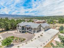 Stunning aerial view of a modern home with lush landscaping and a mountain backdrop, offering privacy and curb appeal at 670 Portland Rd, Monument, CO 80132
