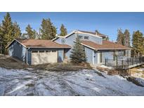 Charming two-story home with a brown roof, blue siding and an attached garage at 27732 Squaw Pass Rd, Evergreen, CO 80439