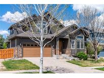 Charming two-story home showcasing stone accents, brown siding, a well-manicured lawn, and a two-car garage at 25871 E 5Th Pl, Aurora, CO 80018