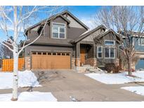 Charming two-story home with a brown wood exterior, attached garage, and snow-covered front yard at 25871 E 5Th Pl, Aurora, CO 80018