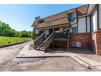Charming townhouse with a brick facade, covered porch and stairs leading to the entrance at 2700 S Holly St # 115, Denver, CO 80222