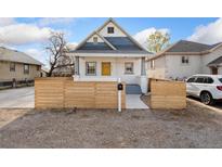 Charming home featuring a yellow front door, and a stylish wooden fence in front of the yard at 5123 Milwaukee St, Denver, CO 80216